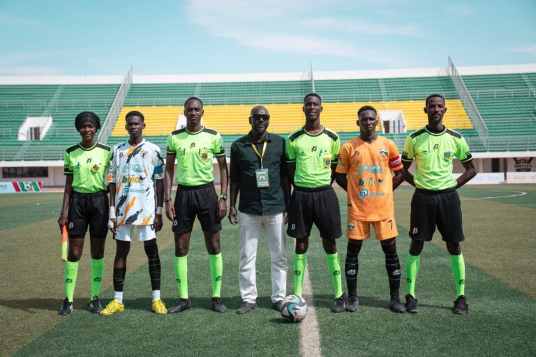 A soccer team with officials posing on a field during daytime at a stadium.