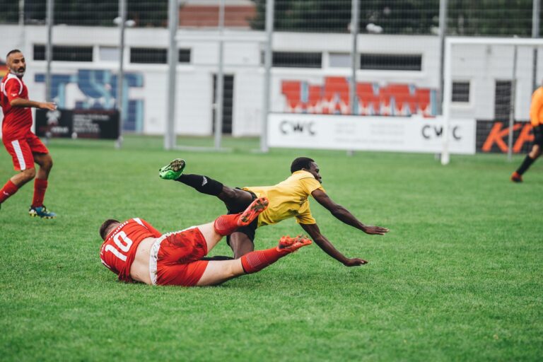 Intense soccer match showing players in motion on a grassy field during the day.