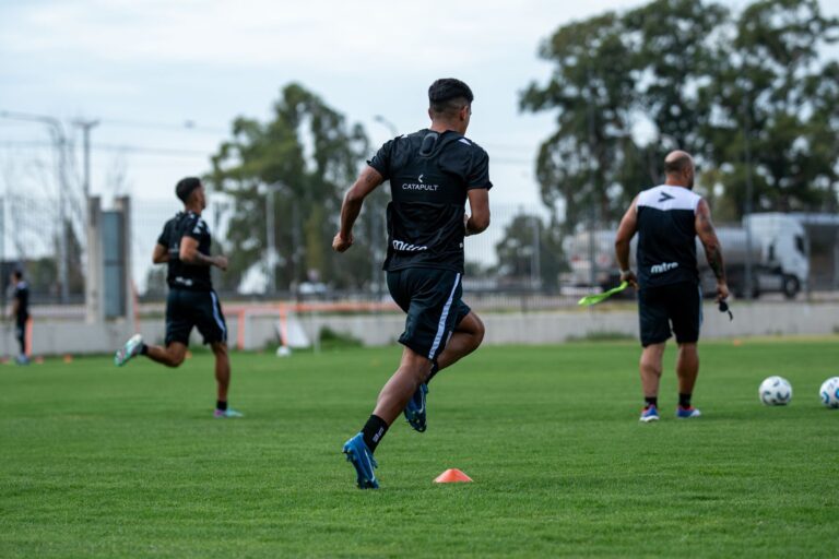 Group of men training on a field, engaging in soccer practice drills in outdoor setting.