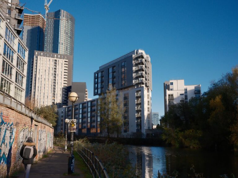 A contemporary city view with skyscrapers by a riverside path, showcasing urban architecture.