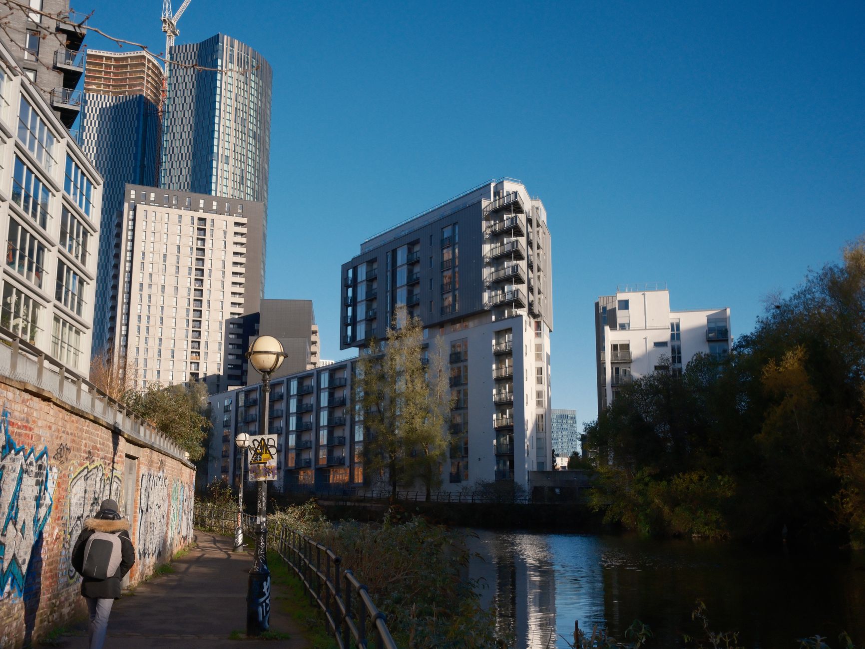 A contemporary city view with skyscrapers by a riverside path, showcasing urban architecture.