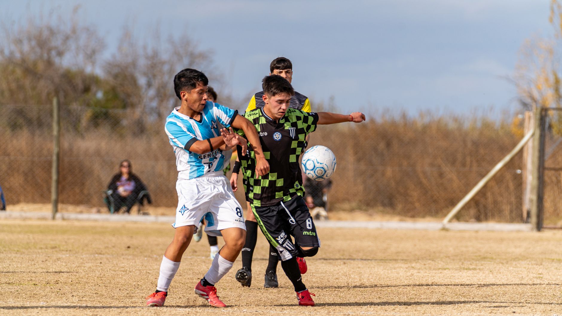 Two young soccer players competing for the ball on a sunny field.