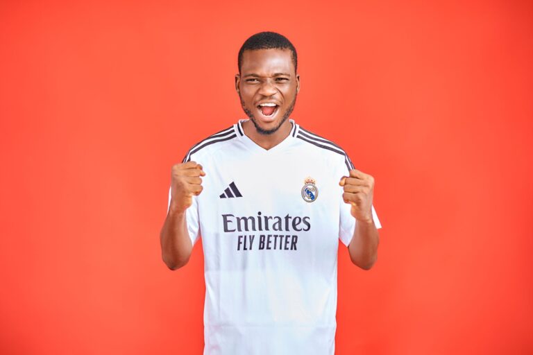 Energetic soccer fan in a team jersey cheering against a vibrant red background.