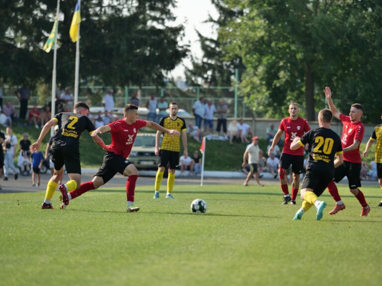 Dynamic action during a football match with teams in black and red jerseys.