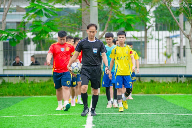 Soccer players and referee entering a field in Hanoi, Vietnam, showcasing teamwork and sportsmanship.