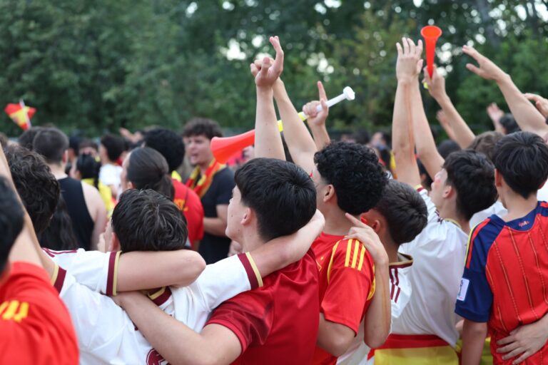 Group of enthusiastic soccer fans celebrating a victory in Madrid, embracing and cheering outdoors.