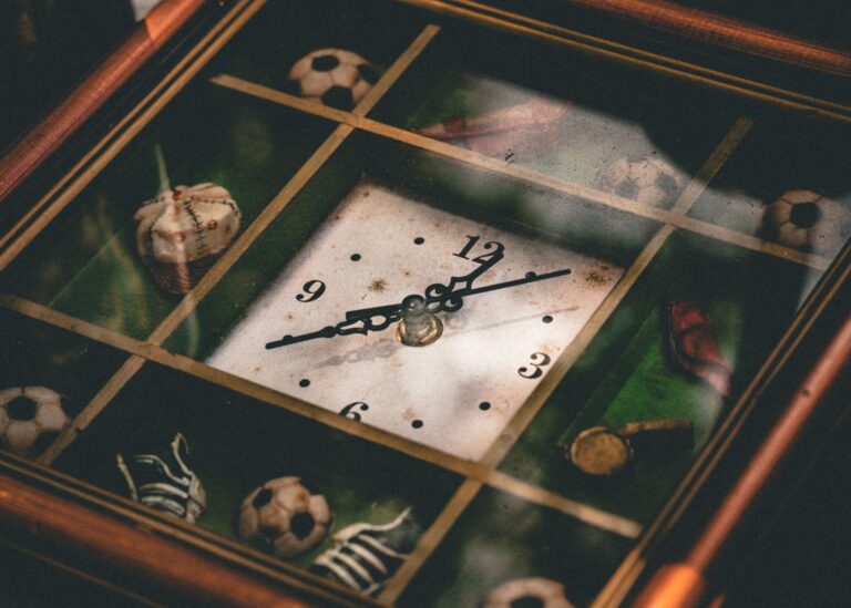 A vintage clock featuring sports-themed decorations like soccer balls and baseballs.