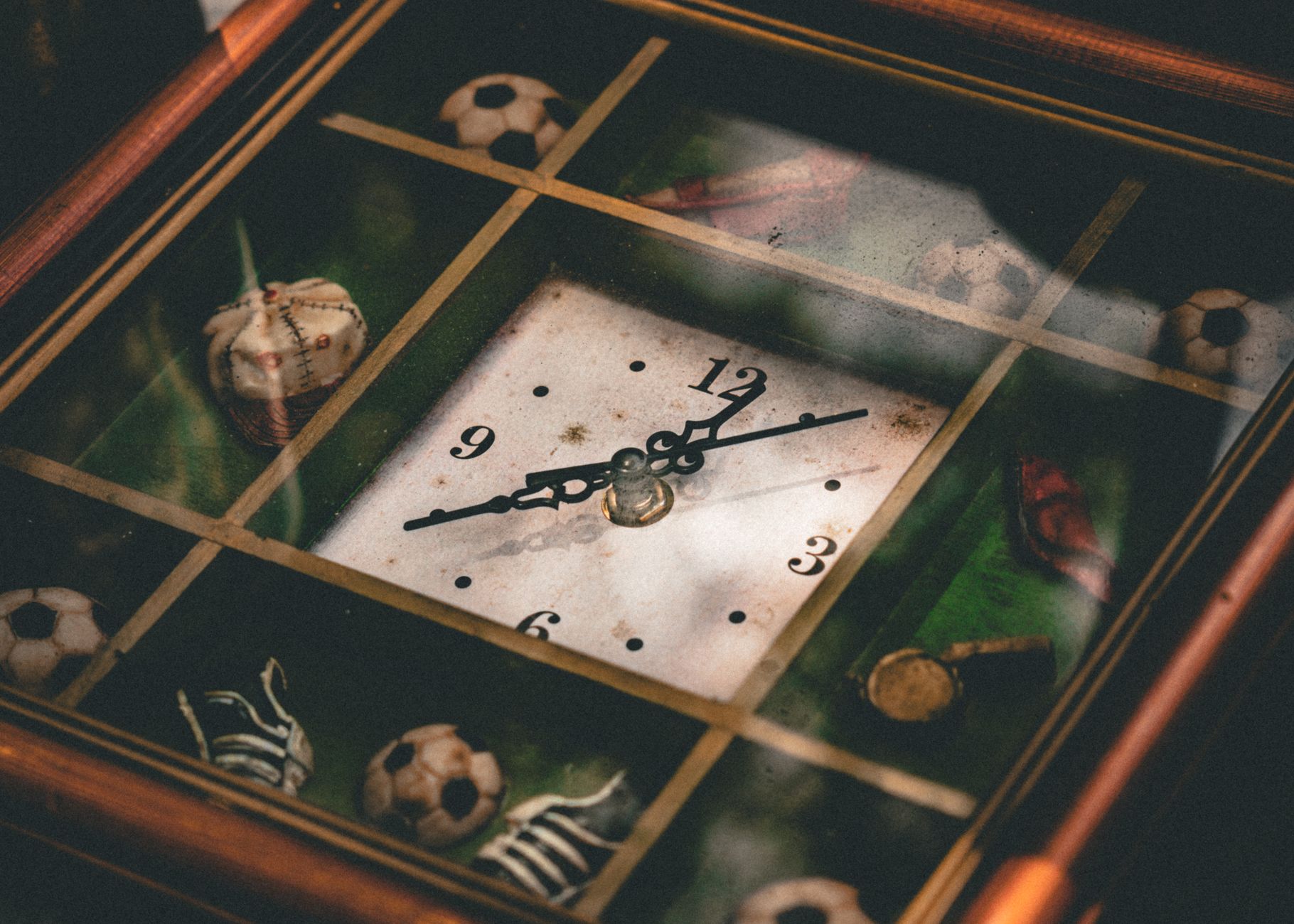 A vintage clock featuring sports-themed decorations like soccer balls and baseballs.