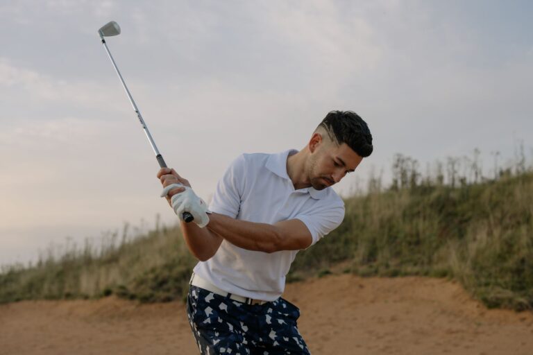 A focused male golfer taking a swing on a picturesque golf course during the day.