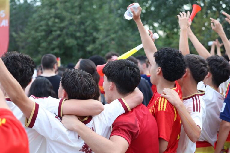 A lively group of young fans celebrating outdoors in Madrid, Spain, showcasing excitement and unity.