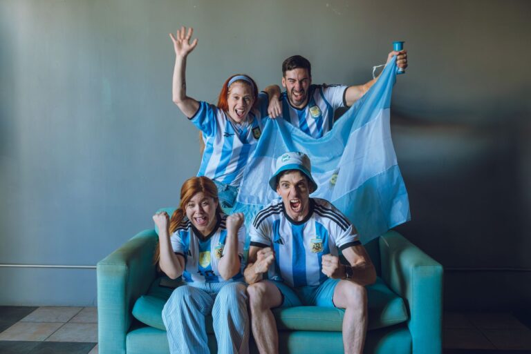 Group of fans celebrating Argentina's soccer victory at home, wearing team jerseys.