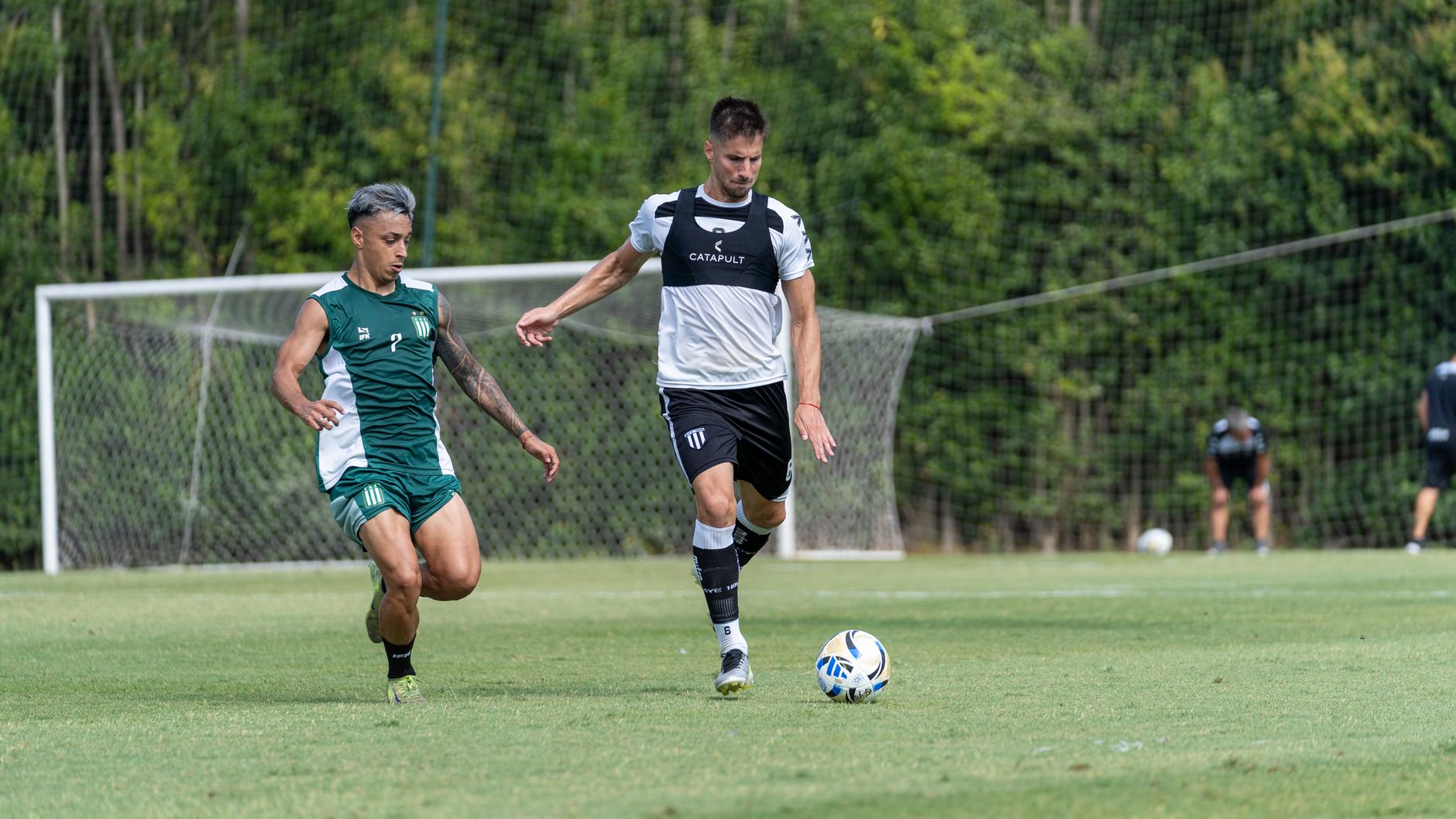 Two male soccer players competing on a grassy field during a daytime match.