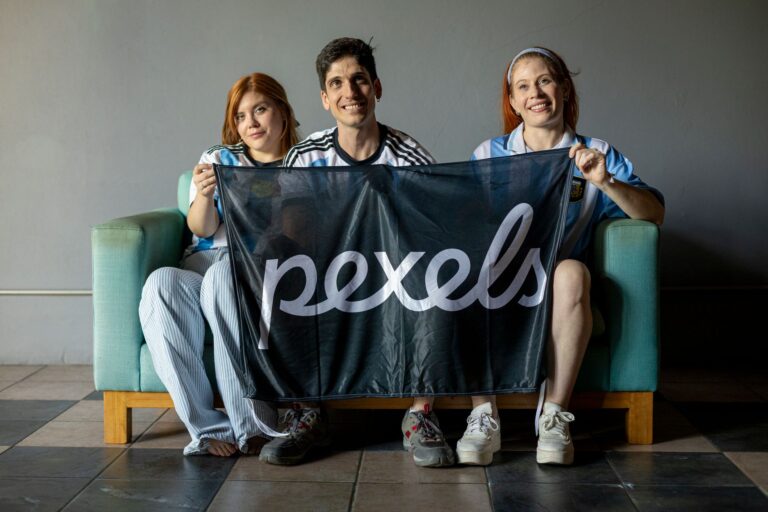 Group of three people holding an Argentina-themed flag indoors, showcasing team spirit.