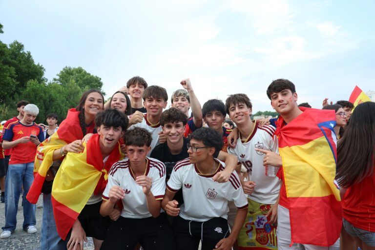 Group of young Spanish fans celebrating their team outdoors with flags and excitement.