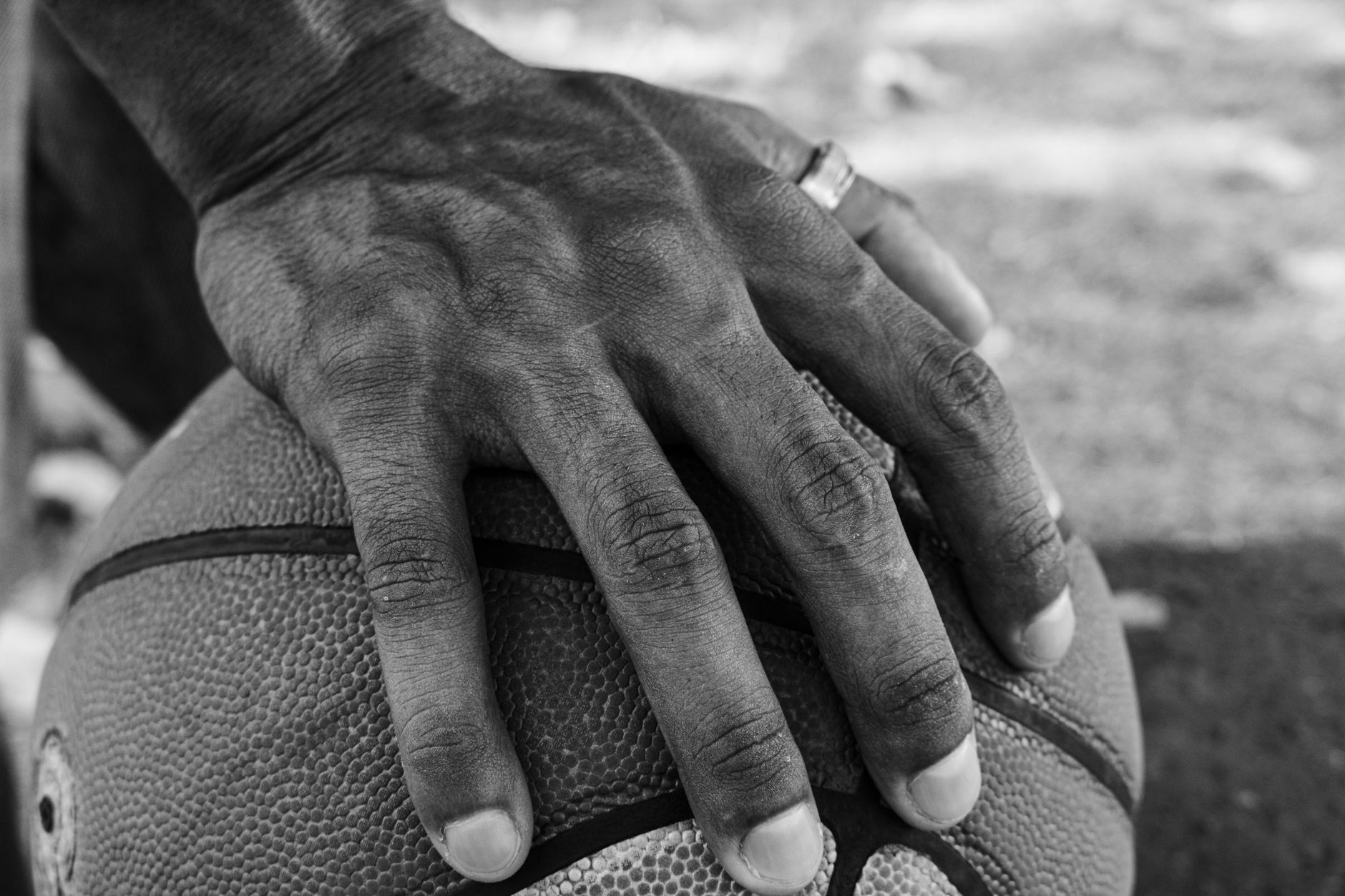 Monochrome image of a hand resting on a basketball, suggesting sports and focus.