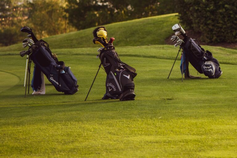 Set of golf bags on a sunlit golf course ready for a game.