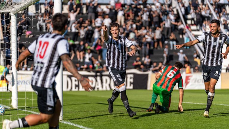 Soccer players in black and white jerseys celebrating a goal during a match.