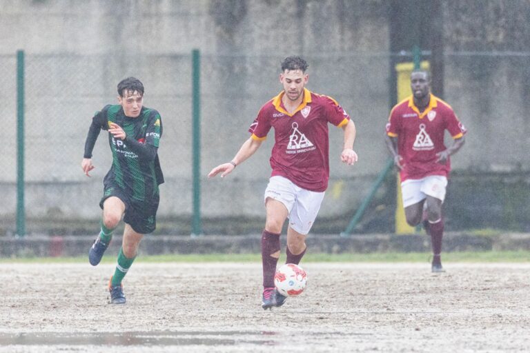 Athletes play soccer in rainy Delianuova, Calabria, Italy, showcasing teamwork and dedication.