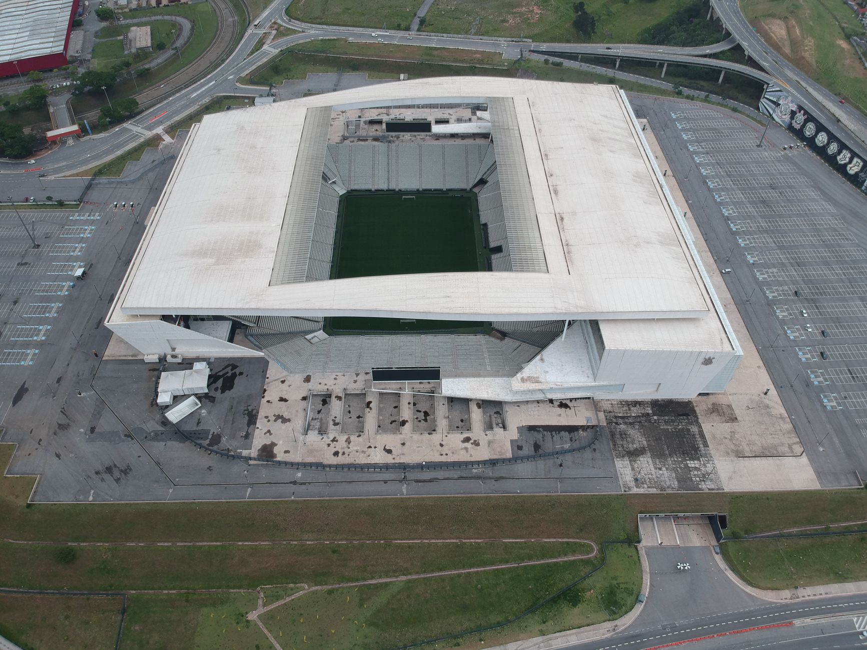 High-angle shot of a contemporary stadium from above, surrounded by parking and roads.