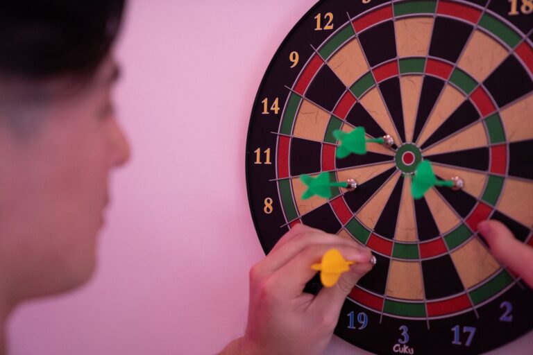 A person focusing on adjusting darts on a dartboard, symbolizing precision and leisure.