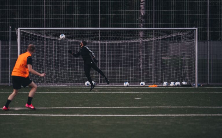 Goalkeeper jumps to save a soccer ball during an outdoor training session on an artificial turf field.
