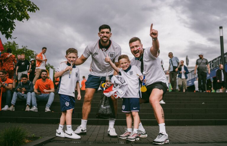Group of enthusiastic soccer fans celebrating victory outside the stadium on game day.