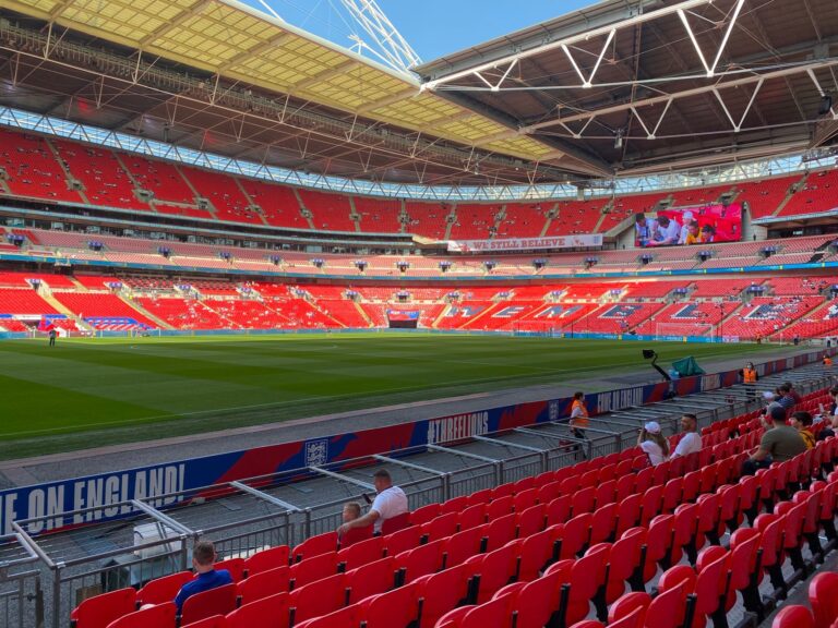 A vibrant view of Wembley Stadium with bright red seats and a well-maintained green field.