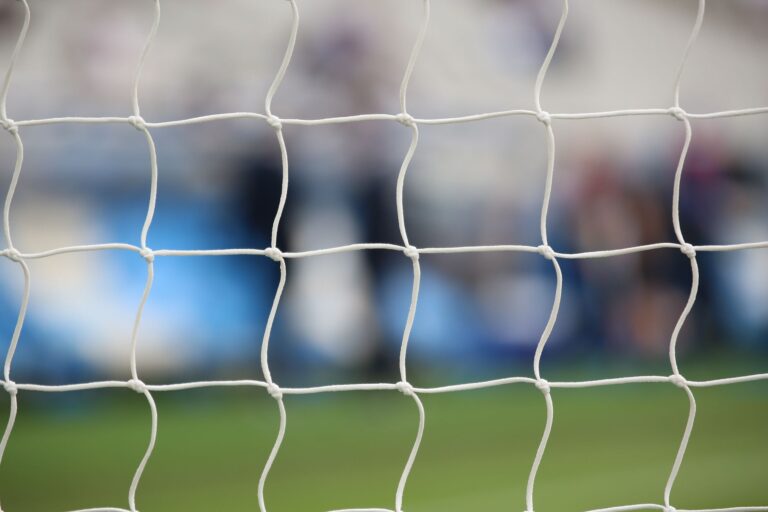 Close-up view of a soccer net with a blurred background of a sports field in Saint-Denis, France.
