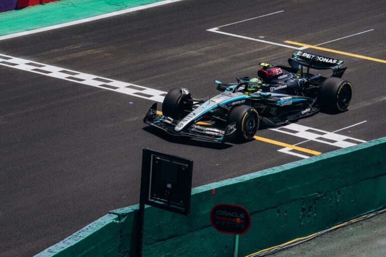 High-speed Formula 1 car crossing the finish line on a race track during the day.