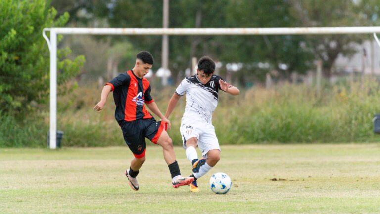 Two young soccer players in action on a grassy field during a competitive match.