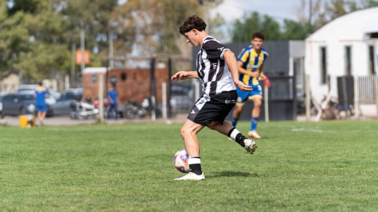 Teenage soccer player in action on green field during daytime match.