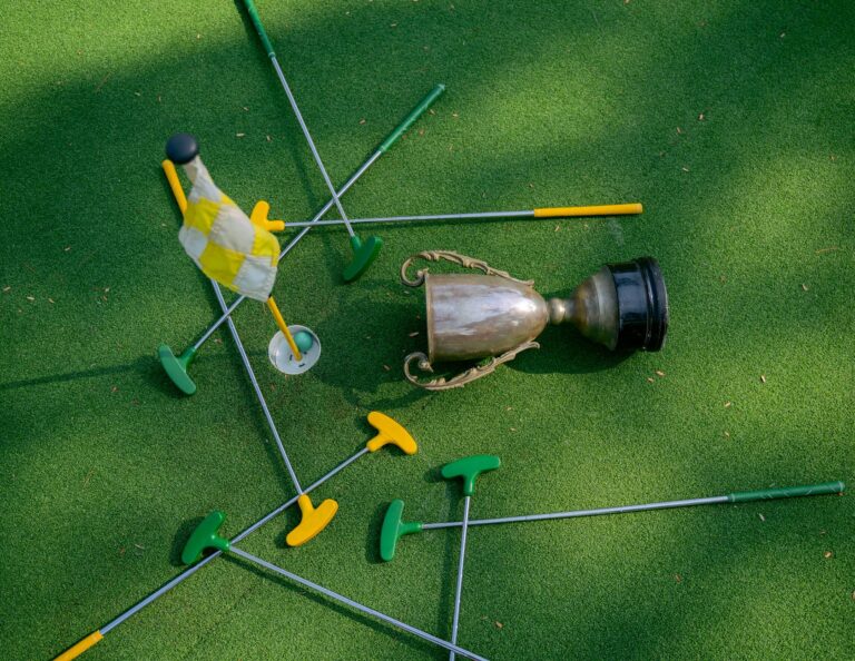 Mini golf setup with colorful putters, a cup, and a flag on green turf. Ideal for casual sports and recreation themes.
