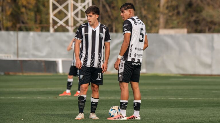 Two young male soccer players stand on a grassy field during a match.