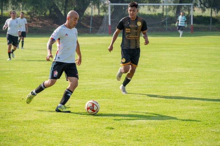 Athletes playing soccer in a competitive match on a vibrant green field.