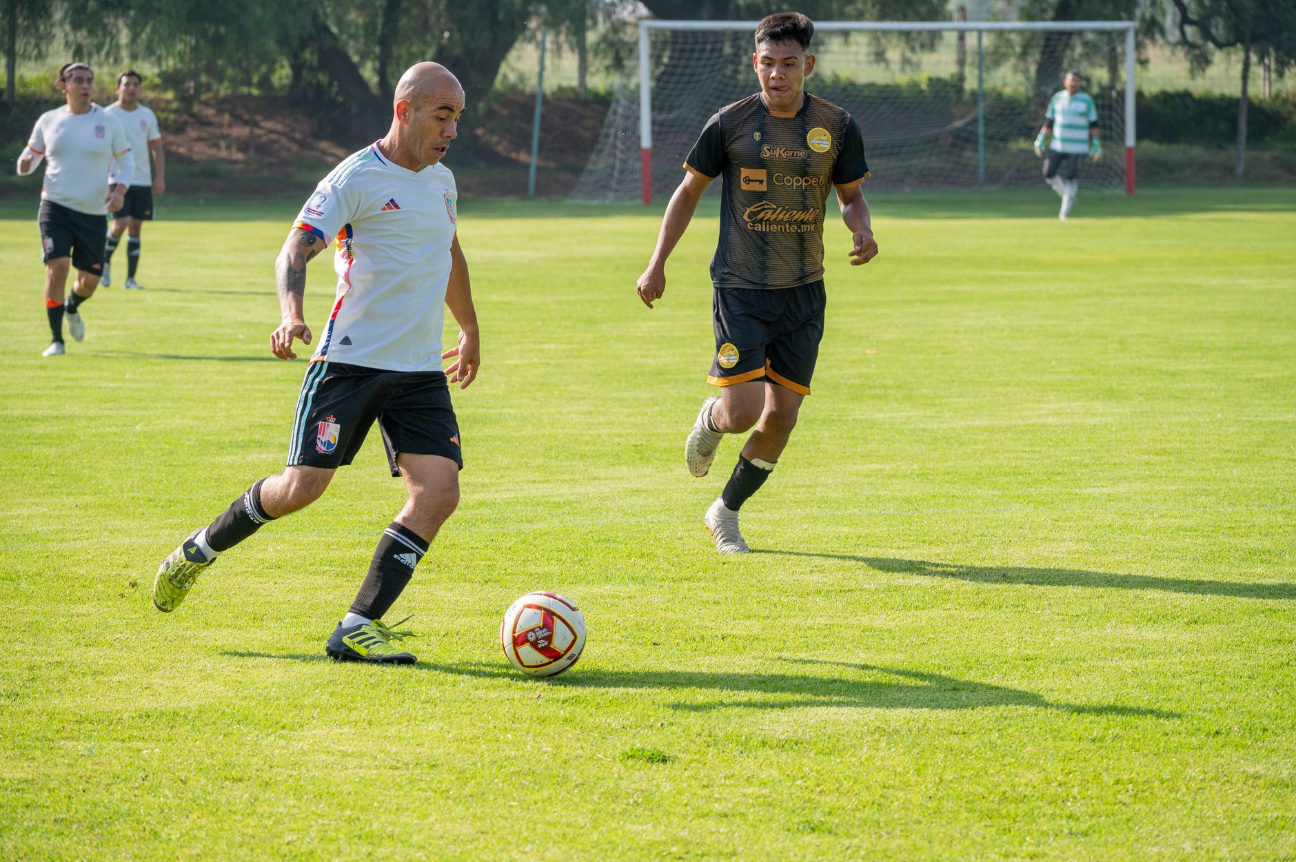 Athletes playing soccer in a competitive match on a vibrant green field.