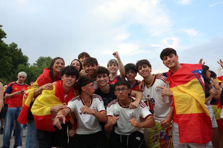 A lively group of young fans joyfully celebrating outdoors with Spanish flags in Madrid, Spain.