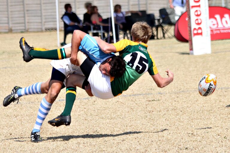 Two rugby players collide mid-air in an action-packed outdoor rugby match.