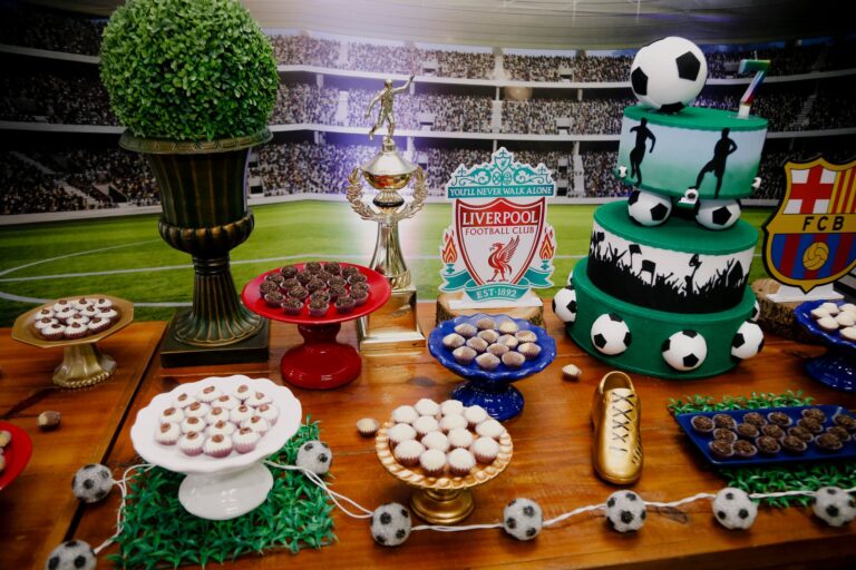 A vibrant soccer-themed dessert table featuring cakes, trophies, and decorations for a birthday party.