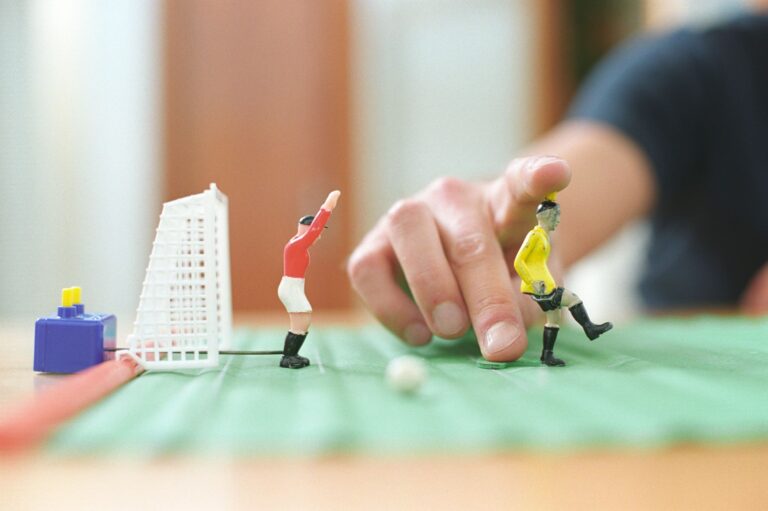 Close-up of a hand manipulating table football toys during a playful game.