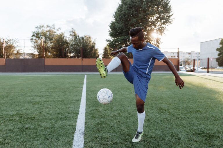 Young football player practicing tricks with a soccer ball on a sunny day outdoors.