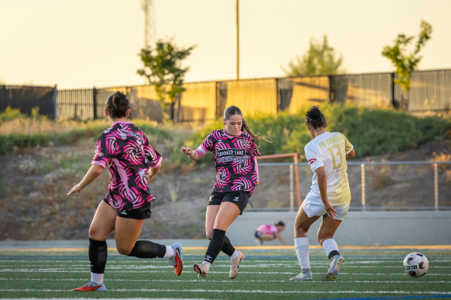Dynamic women playing soccer on a sunny day, showcasing teamwork and athleticism outdoors.
