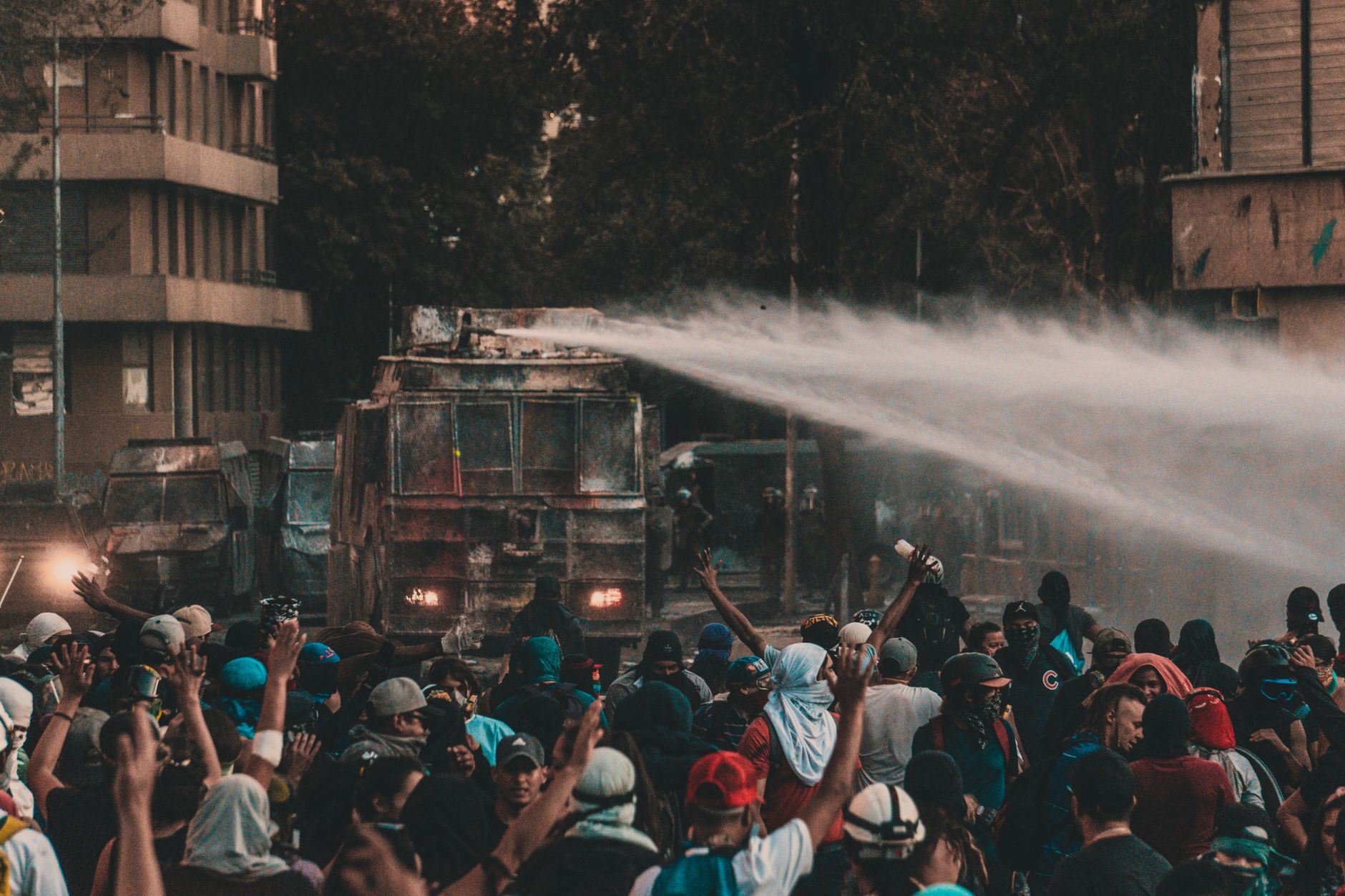 A large protest in Santiago, Chile, with water cannon trucks and a crowd of demonstrators.