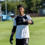 Young soccer player giving thumbs up on training field. Outdoor sports photography.