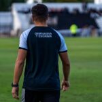 Back view of soccer coach at Gimnasia y Esgrima stadium during a match.