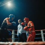 Two boxers engaged in an intense match under arena lights in Madrid.