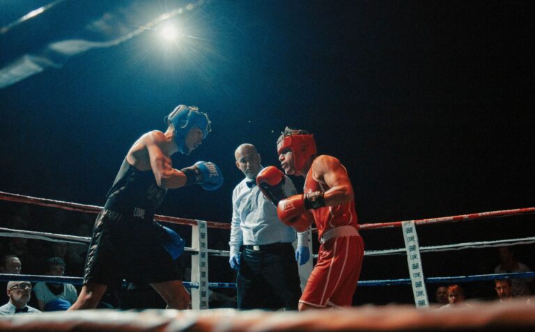Two boxers engaged in an intense match under arena lights in Madrid.