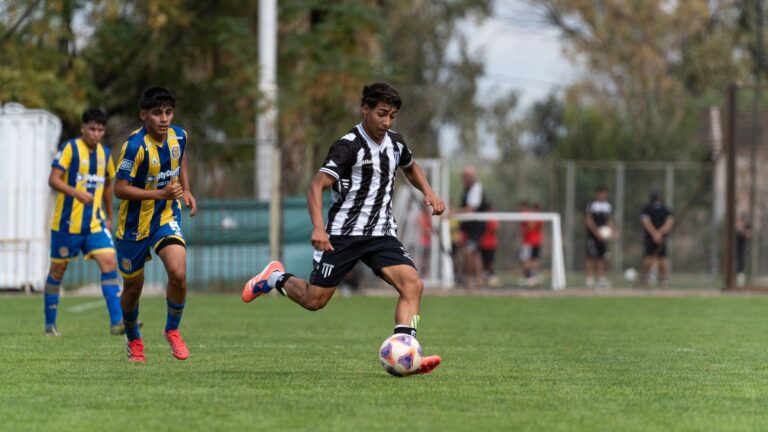Teen soccer player skillfully dribbles during an outdoor match on a clear day.