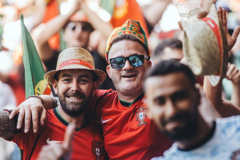 Enthusiastic soccer fans with flags and hats enjoying a lively match.