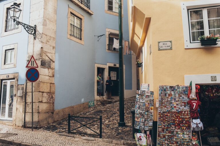 A picturesque street in Lisbon featuring colorful buildings and a vibrant souvenir shop.