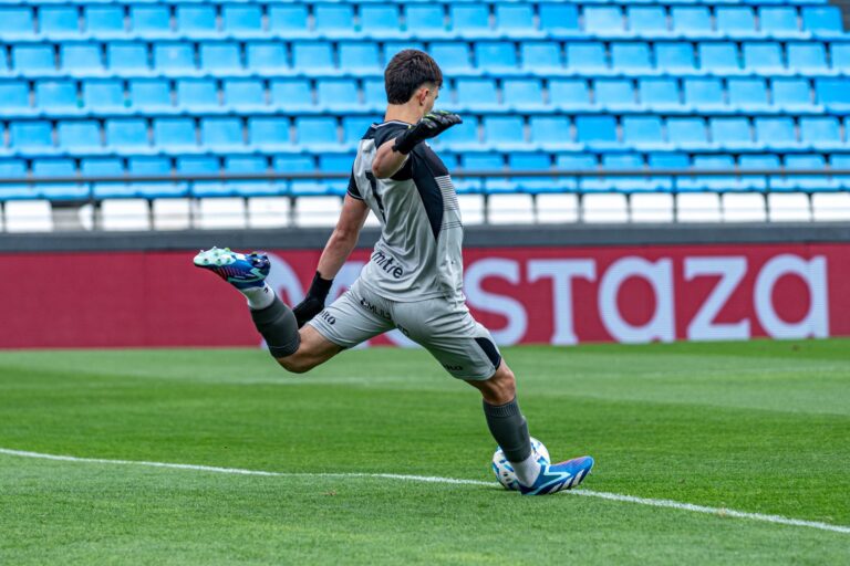 Soccer goalkeeper kicks the ball during a game on the field.